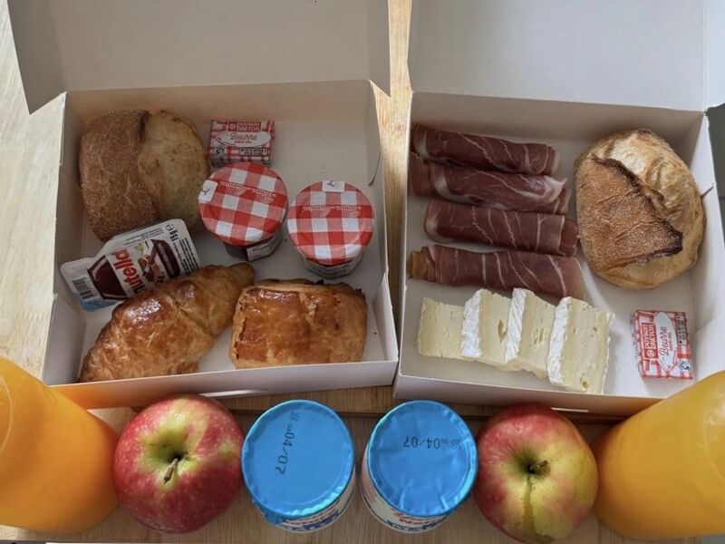 Coffrets petit-déjeuner avec jus d'orange, viennoiseries, confitures, yaourts et pommes