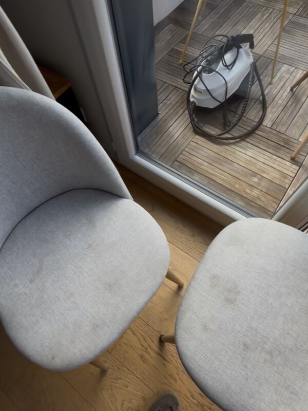 Chaises en tissu gris tachées, avec le nettoyeur vapeur en arrière-plan