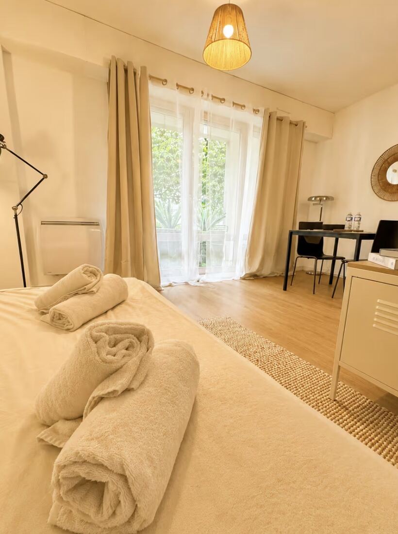 Chambre préparée avec serviettes roulées sur le lit, dans un logement géré par NVJ